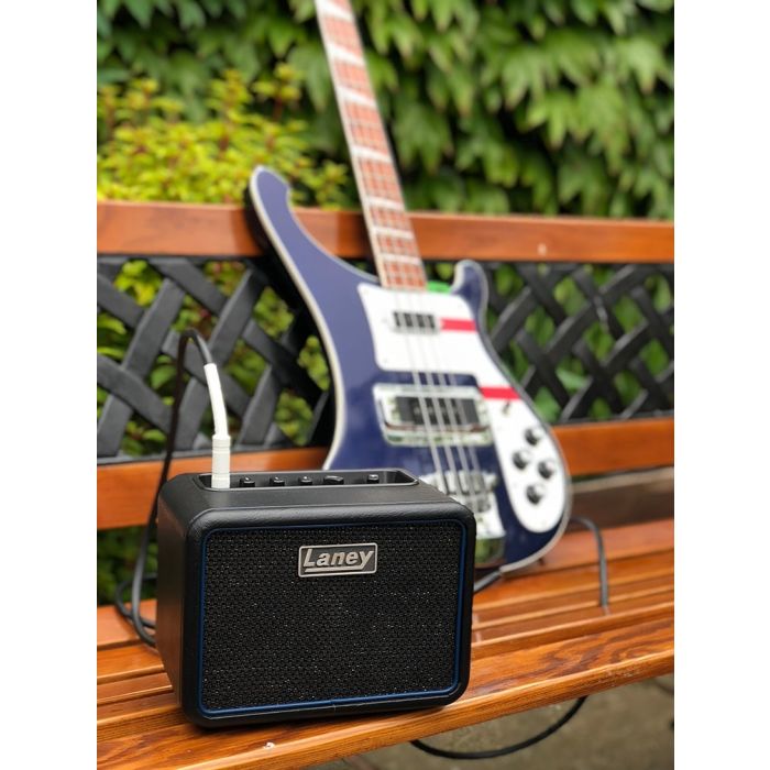 Laney Mini-Bass-NX Portable Mini Bass Amplifier On A Bench Next To A Rickenbacker Bass