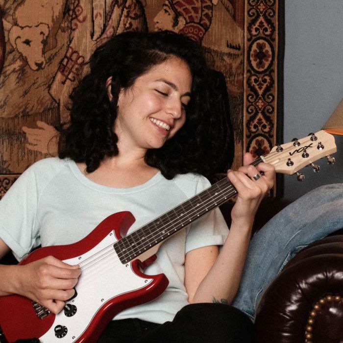 Woman Playing the Vox SDC-1 Mini Electric Guitar On A Sofa